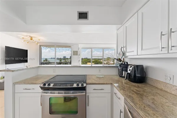 a kitchen with stainless steel appliances granite countertop a stove a sink and a microwave