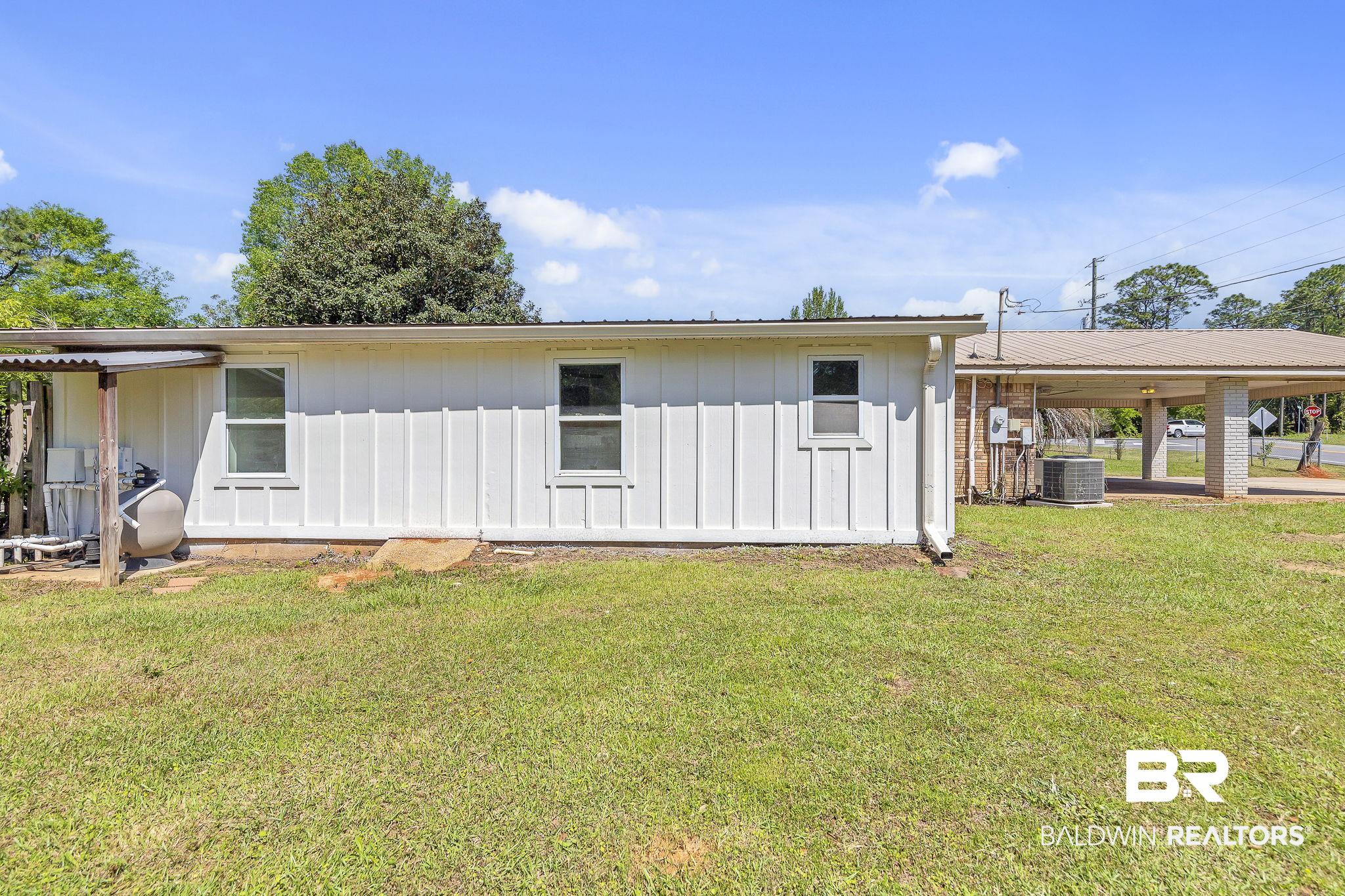 11964 Stroh Road Daphne, AL 36527 - Photo 47 of 58 Rear view of house with a carport, central air condition unit, board and batten siding, and a lawn
