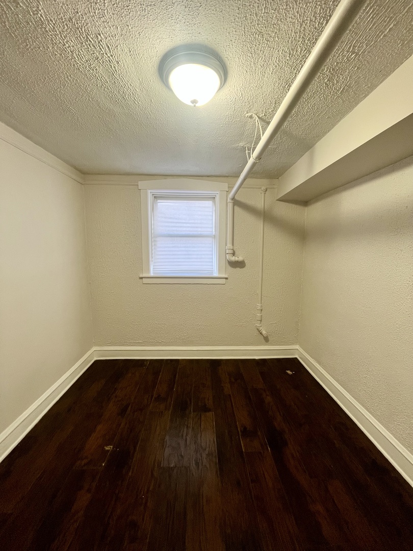3636 West Iowa Street, Unit BF Chicago, IL 60651 - Photo 6 of 14 a view of an empty room with wooden floor and a window