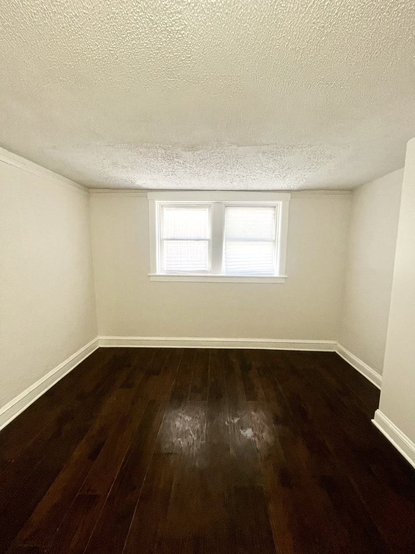 3636 West Iowa Street, Unit BF Chicago, IL 60651 - Photo 10 of 14 an empty room with wooden floor and windows