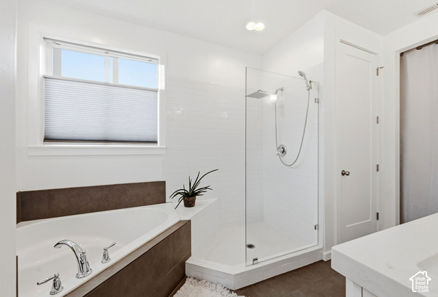 1295 North Canyon View Road Midway, UT 84049 - Photo 27 of 52 Freestanding soaking tub with chrome fixtures, glass-enclosed shower with a rainfall showerhead, white subway tile surround, and neutral-toned flooring