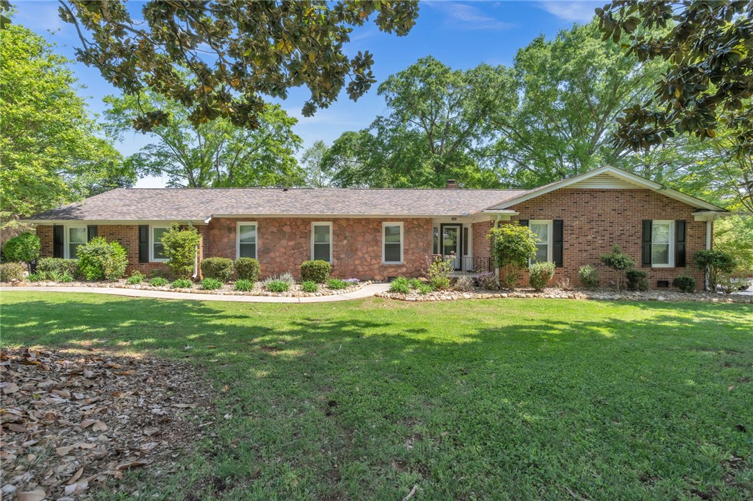 This charming home offers a brick and stone facade, nestled amongst lush trees.