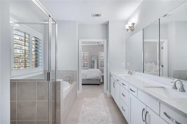 a en suite bathroom with a double vanity sink a large mirror and shower