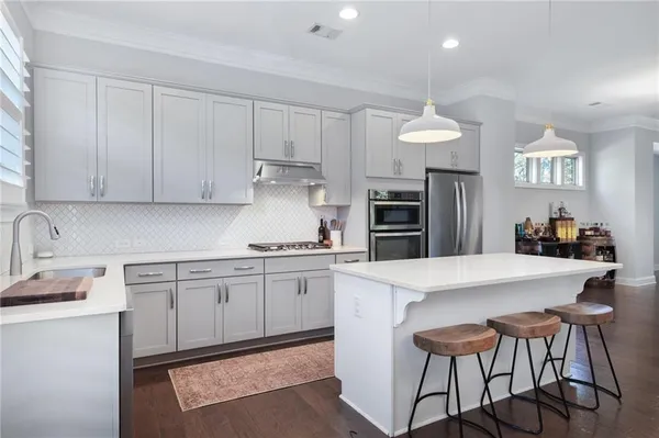 a kitchen with stainless steel appliances granite countertop a sink a stove a refrigerator and island with wooden floor