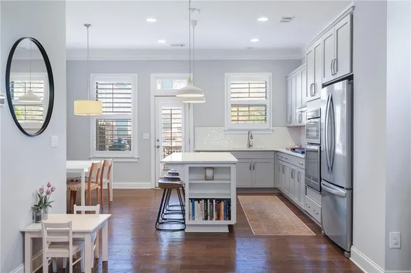 a kitchen with stainless steel appliances granite countertop a refrigerator a sink dishwasher a dining table and chairs with wooden floor