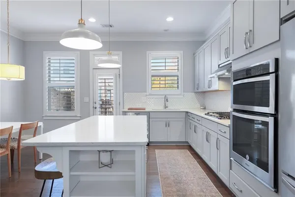 a kitchen with stainless steel appliances granite countertop a kitchen island hardwood floor sink stove dining table and chairs