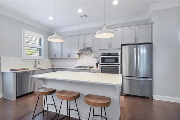 a kitchen with kitchen island a counter space a sink stainless steel appliances and cabinets