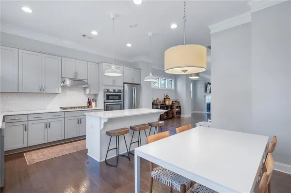 a kitchen with stainless steel appliances granite countertop a table chairs sink and cabinets