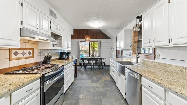 a kitchen with stainless steel appliances granite countertop a stove a sink and a refrigerator