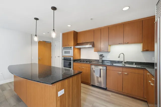 a kitchen with stainless steel appliances granite countertop a sink a stove and a refrigerator
