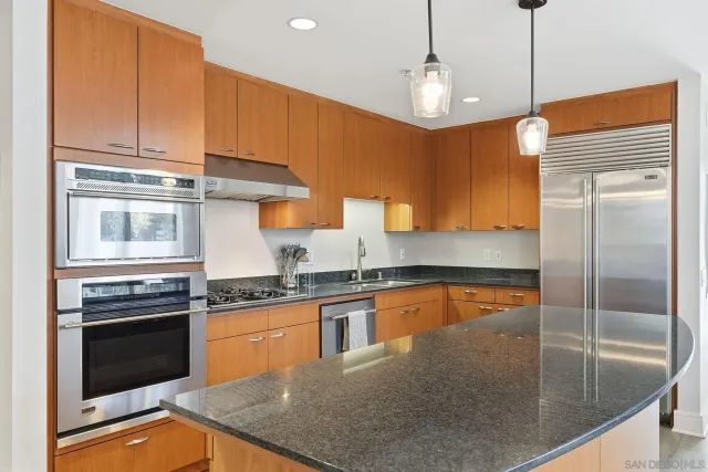 a kitchen with stainless steel appliances granite countertop a stove a sink and a refrigerator