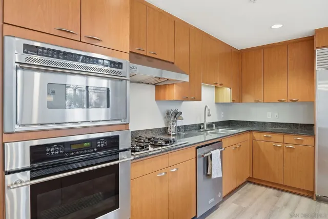 a kitchen with granite countertop stainless steel appliances a stove a sink and cabinets