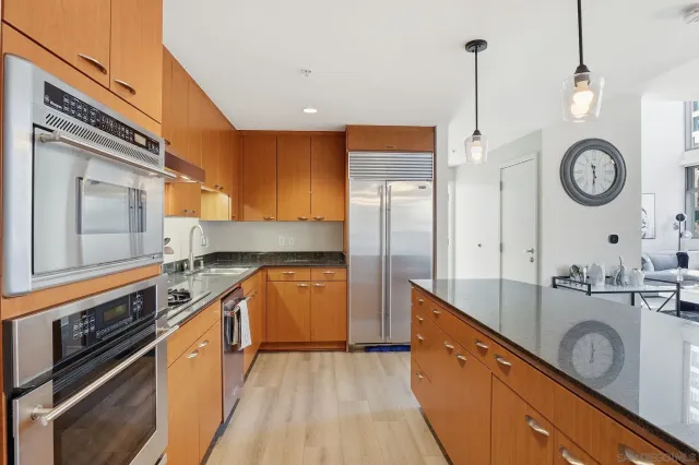 a large kitchen with stainless steel appliances granite countertop a sink a stove and a wooden floors