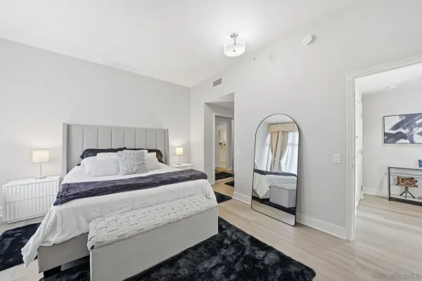 a bedroom with a bed a mirror on dresser and a window