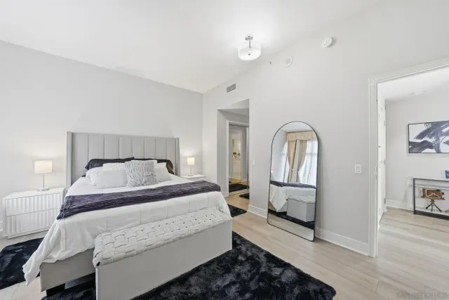 a bedroom with a bed a mirror on dresser and a window