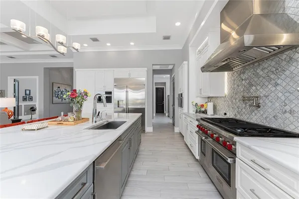 a large white kitchen with lots of furniture and stainless steel appliances