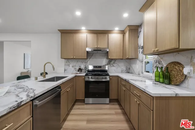 a kitchen with stainless steel appliances granite countertop a stove a sink a refrigerator and a microwave