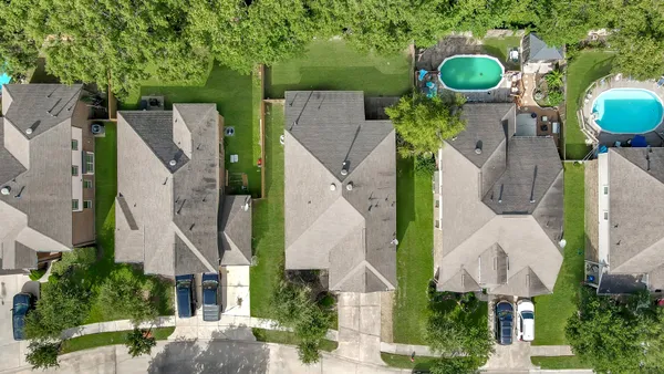 an aerial view of residential houses with outdoor space and trees