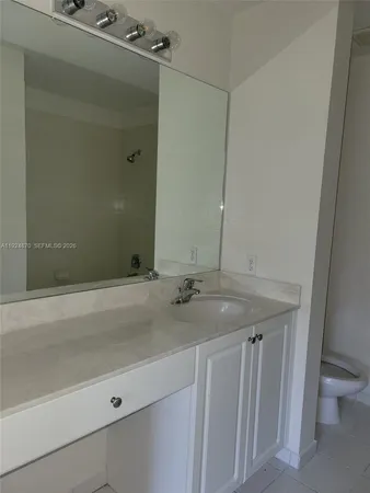a bathroom with a granite countertop sink and a toilet