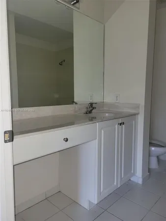 a bathroom with a granite countertop sink and a toilet