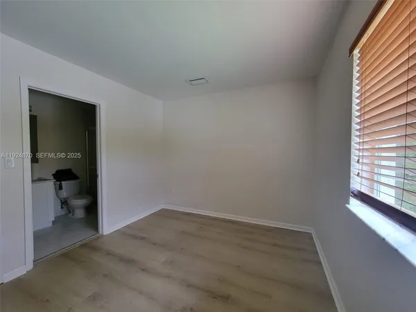 an empty room and a bathroom with toilet