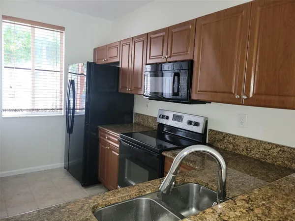 a kitchen with granite countertop a stove sink and cabinets