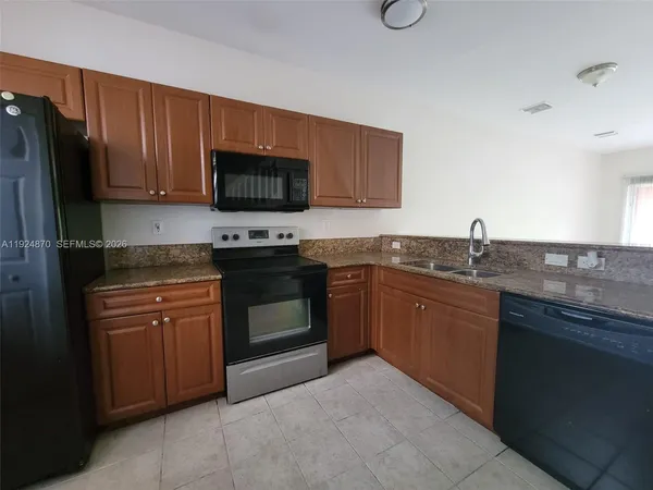 a kitchen with granite countertop wooden cabinets and a stove top oven