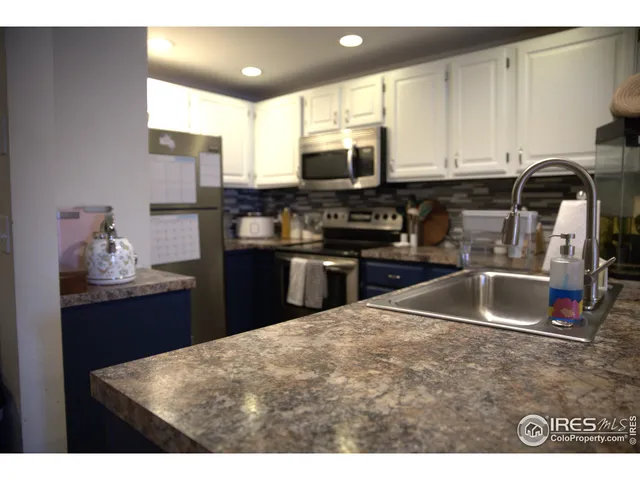 a kitchen with kitchen island granite countertop a sink stainless steel appliances and cabinets