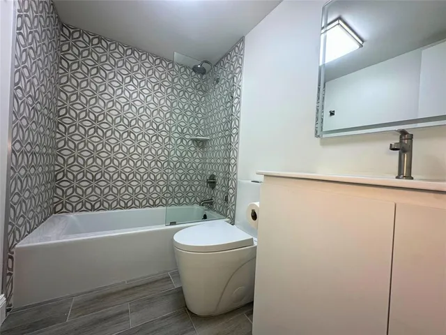 a bathroom with a bathtub sink vanity mirror and toilet