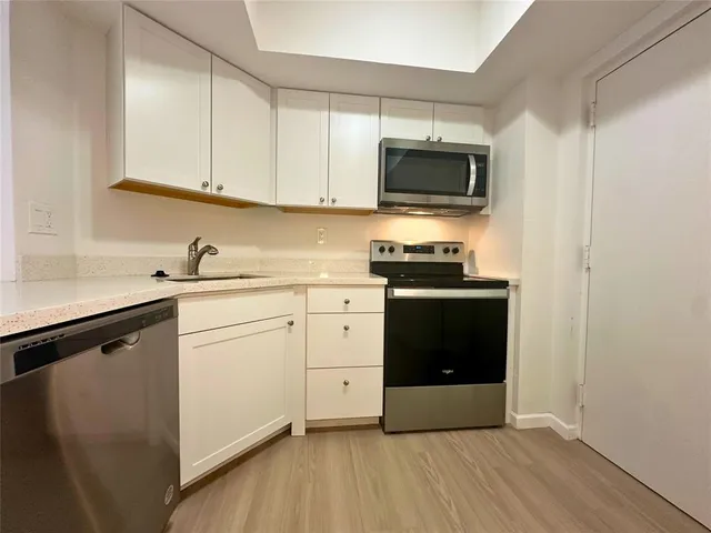 a kitchen with stainless steel appliances a stove microwave and sink
