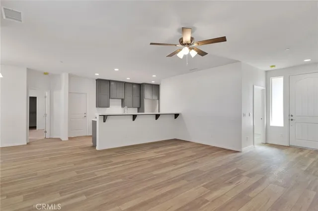 a view of an empty room with wooden floor and a ceiling fan