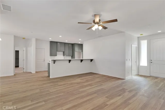 a view of an empty room with wooden floor and a ceiling fan
