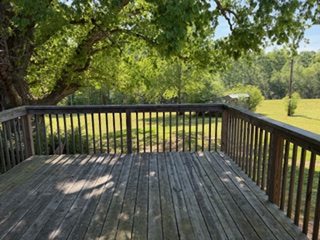 103 Gilkeson Road Honea Path, SC 29654 - Photo 9 of 25 This spacious wooden deck offers serene outdoor living amidst lush greenery.