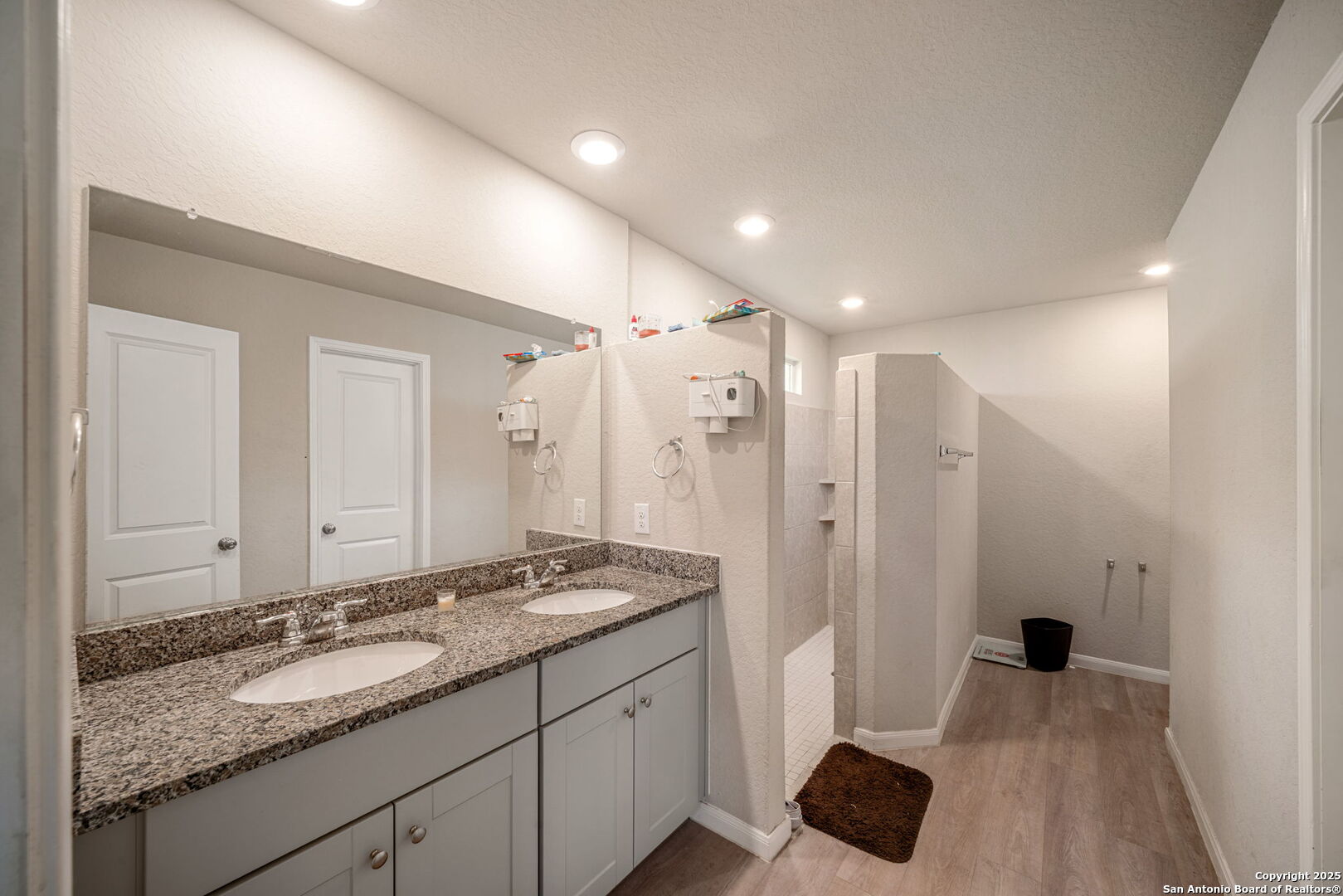 31646 Untrodden Way Bulverde, TX 78163 - Photo 14 of 36 a bathroom with a granite countertop sink a mirror and a shower