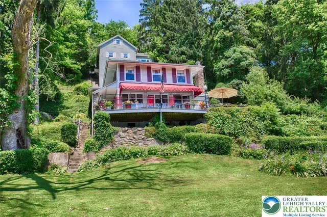 a view of a house with a big yard and large trees