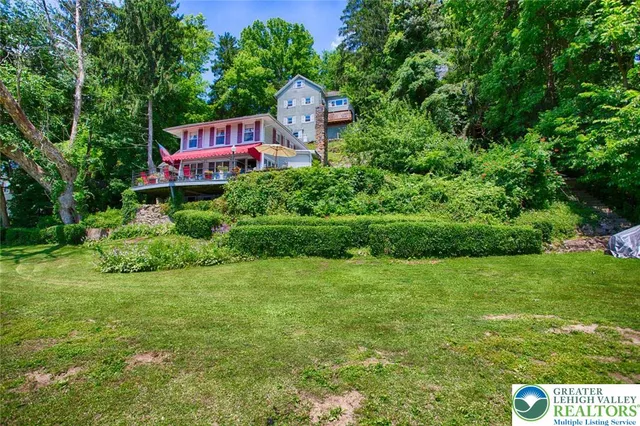 a view of a house with a big yard and large trees