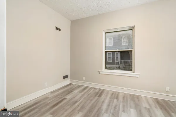 an empty room with wooden floor cabinet and windows