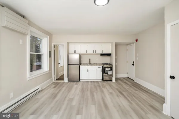 a view of empty room with wooden floor and electronic appliances