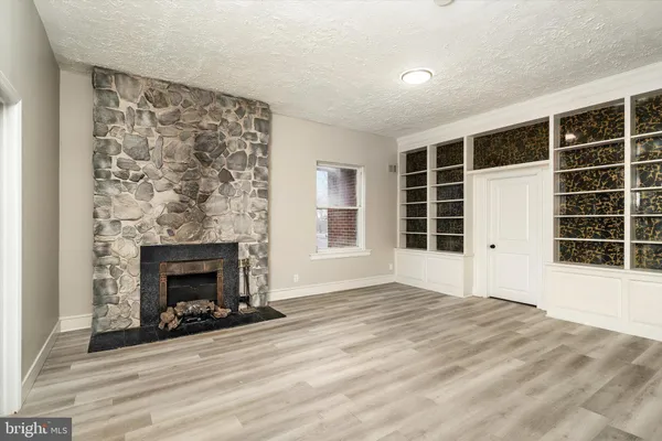 a view of an empty room with a fireplace and windows