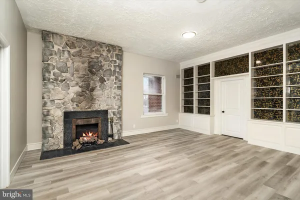a view of an empty room with a fireplace and windows