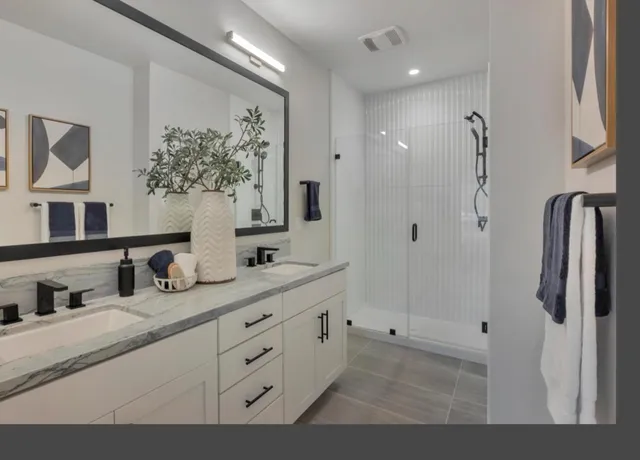 a bathroom with a double vanity sink mirror and shower