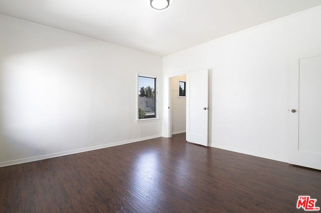 an empty room with wooden floor and white walls