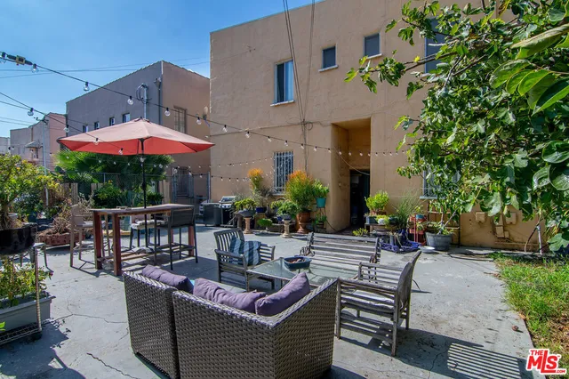 a view of a patio with couches and table and chairs under an umbrella with a fire pit