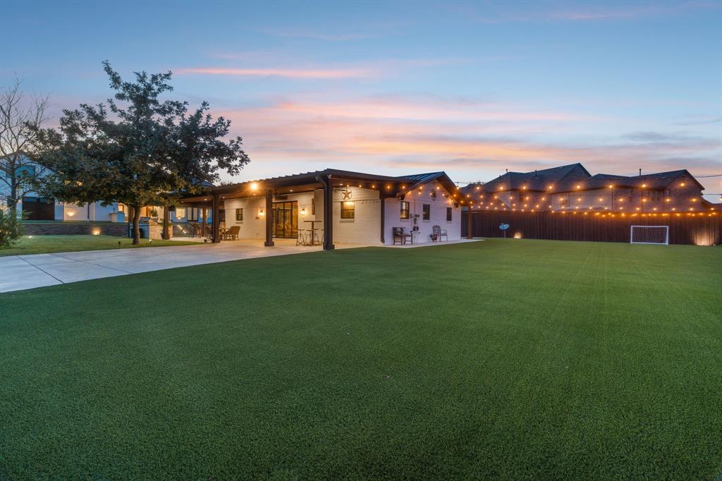 a view of a field with cars parked in front of house