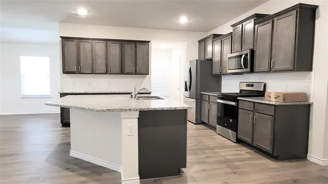 a kitchen with stainless steel appliances granite countertop a refrigerator a sink and a stove