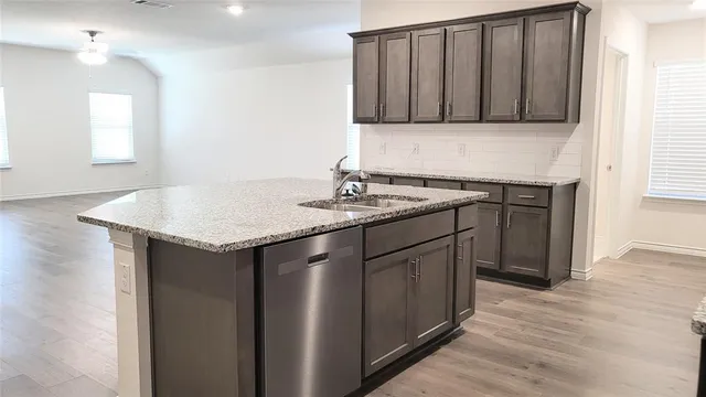 a kitchen with stainless steel appliances granite countertop a sink and a wooden floor