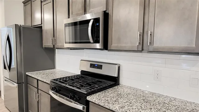 a kitchen with stainless steel appliances granite countertop a refrigerator and a stove top oven