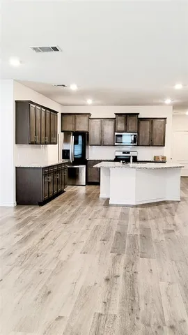 a large white kitchen with stainless steel appliances kitchen island granite countertop a sink and cabinets