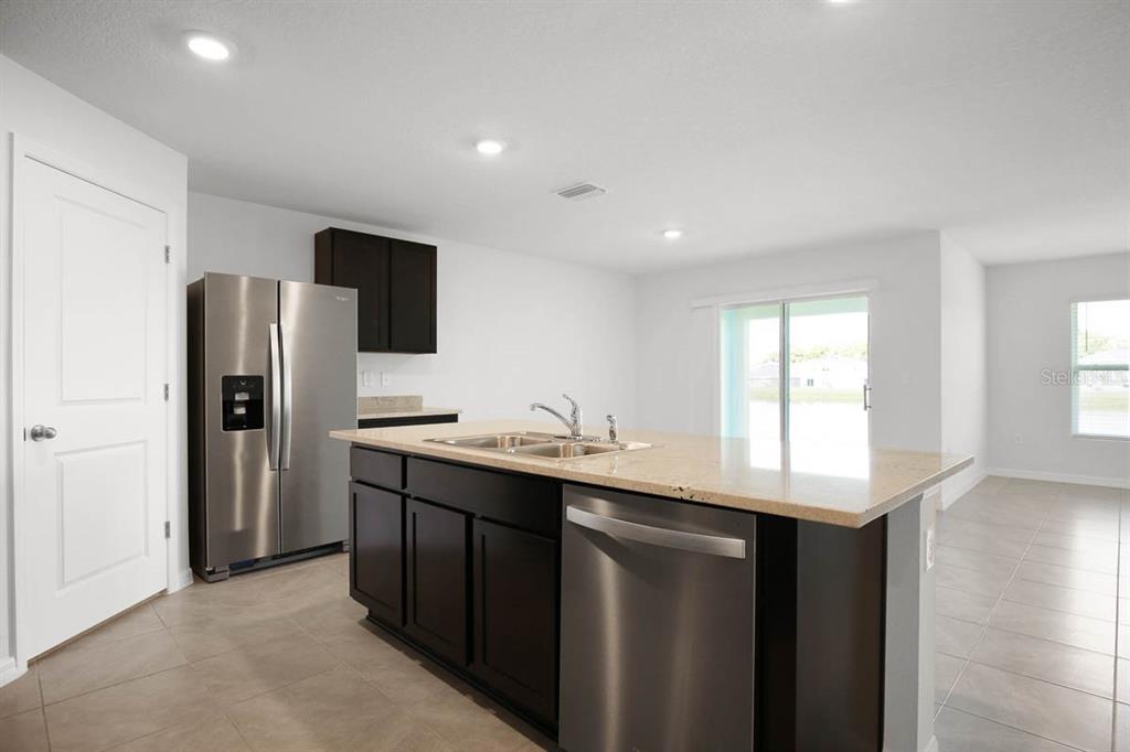 16530 Windmill Forge Pass Wimauma, FL 33598 - Photo 7 of 33 a kitchen with stainless steel appliances granite countertop a sink a refrigerator and a stove