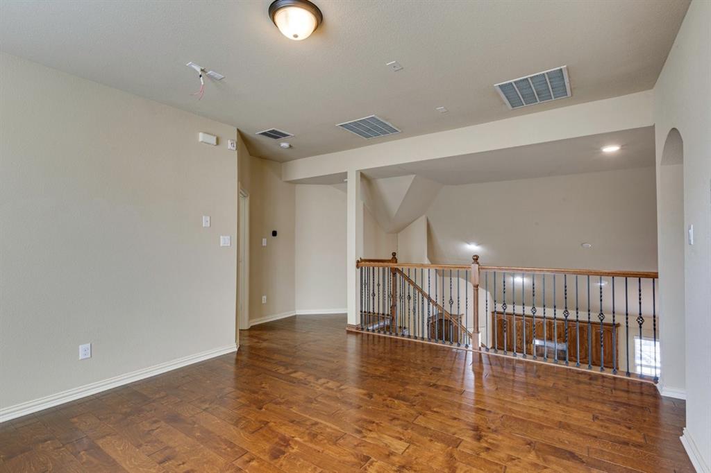 1522 Blue Jay Road Garland, TX 75043 - Photo 27 of 32 Spacious room featuring wood-finish flooring, light neutral wall tones, and a staircase with an iron-spindled railing
